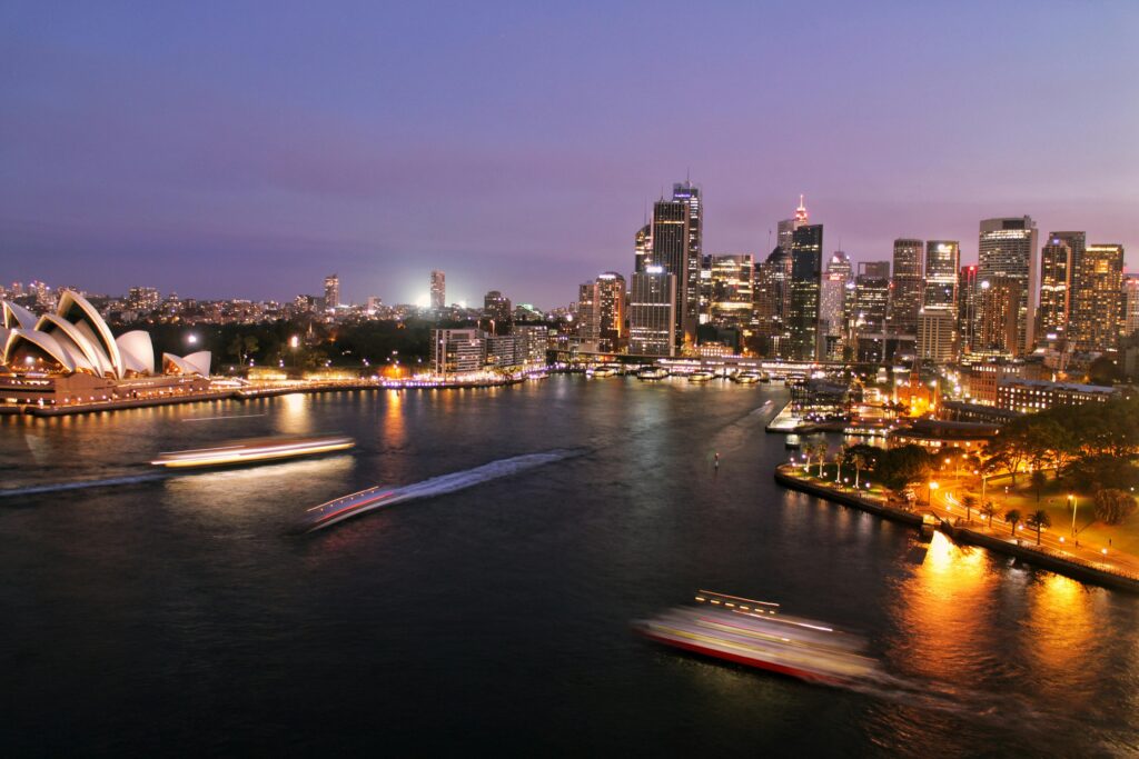 pexels-photo-995764-995764 Captivating view of Sydney's illuminated skyline with the iconic Opera House and harbor at night.