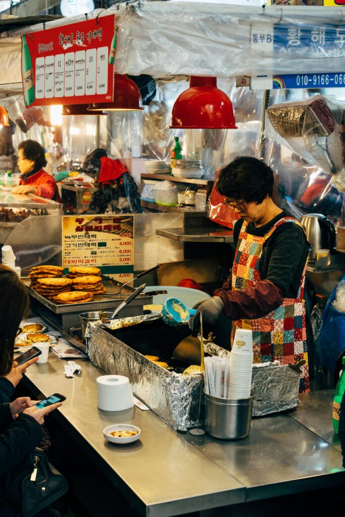 pexels-photo-5059928-5059928 Vibrant street food scene in Seoul showcasing vendor frying traditional Korean pancakes.