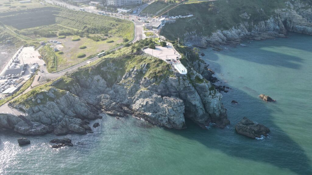 pexels-photo-12184974-12184974 Stunning aerial view of a rocky coastline and scenic road during the day.