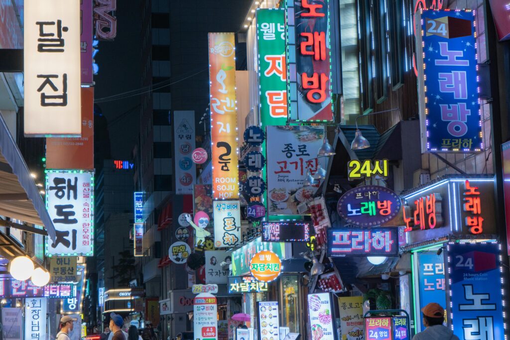 pexels-photo-13679285-13679285-1 Explore the bustling night scene of Myeongdong with neon signs and vibrant city lights in Seoul, South Korea.