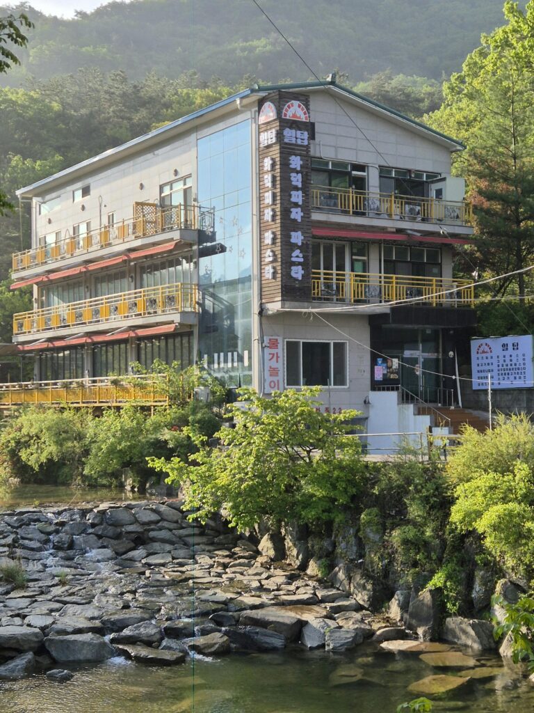 pexels-photo-36104185-36104185 A modern building by a tranquil river with lush greenery in a peaceful setting.