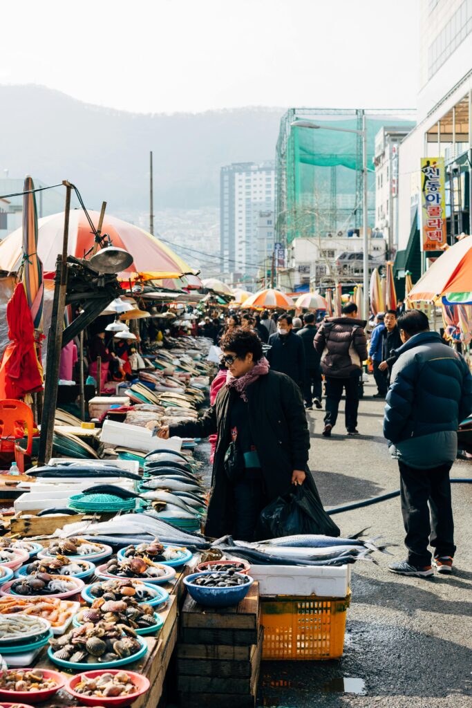 pexels-photo-5051604-5051604 Explore a bustling street market in Busan, with vivid stalls and diverse crowds in vibrant urban setting.